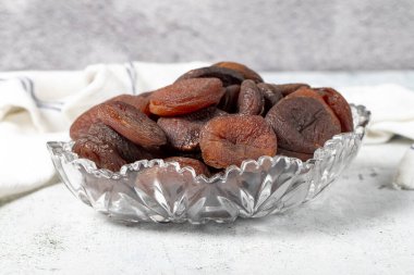 Dried apricots on stone background. Dark dried apricots in a glass bowl. Diet foods. close up