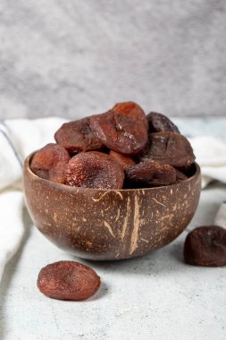 Dried apricots on stone background. Dark dried apricots in a glass bowl. Diet foods. close up