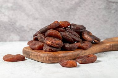 Dried apricots on stone background. Dark dried apricots on a wooden serving board. Diet foods. close up
