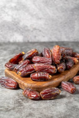 Date fruit on a dark background. Organic pile of medjoul dates on a wood serving board. Ramadan food. close up