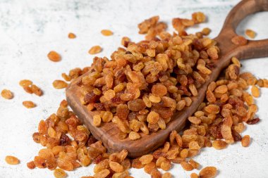 Raisins on stone background. Organic pile of yellow raisins on a wooden serving board. Dried healthy nuts. close up