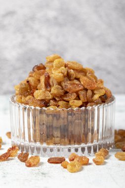 Raisins on stone background. Organic yellow raisins in a glass bowl. Dried healthy nuts. close up