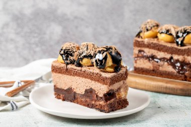 Chocolate and profiteroles cake. Layered cake with chocolate and cream on plate on stone background. close up