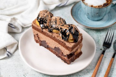 Chocolate and profiteroles cake. Layered cake with chocolate and cream on plate on stone background. close up