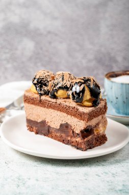 Chocolate and profiteroles cake. Layered cake with chocolate and cream on plate on stone background. close up