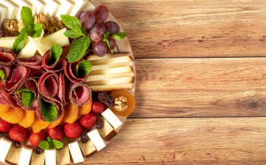 Antipasto catering platter with salami and cheese on a wooden background. Copy space. Empty space for text