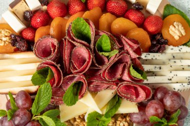 Cold Smoked Meat Plate, antipasto set platter wooden plate. Antipasto board with sliced meat, ham, salami, cheese. Side view with close up