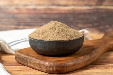 Black pepper spice. Ground black pepper spice in bowl on wood floor. Dry spice concept. close up