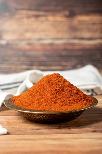 Red chili powder spice. Ground sweet paprika spice in bowl on wood background. Dry spice concept. close up