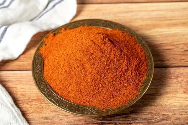Red chili powder spice. Ground sweet paprika spice in bowl on wood background. Dry spice concept. close up