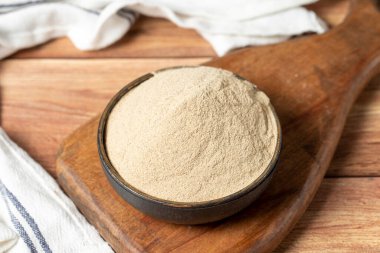 Powdered white pepper spice. Ground powdered white peppercorns in a bowl on a wooden background. Dry spice concept. close up