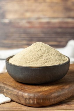 Powdered white pepper spice. Ground powdered white peppercorns in a bowl on a wooden background. Dry spice concept. close up