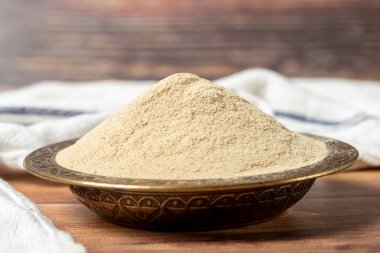 Powdered white pepper spice. Ground powdered white peppercorns in a bowl on a wooden background. Dry spice concept. close up