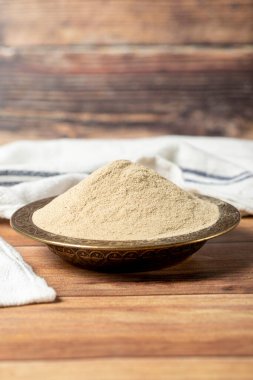 Powdered white pepper spice. Ground powdered white peppercorns in a bowl on a wooden background. Dry spice concept. close up