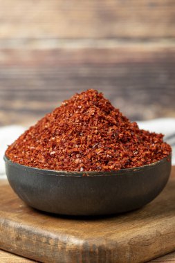 Red pepper flakes. Crushed chili pepper in bowl, dried chili flakes on wooden background. Close up
