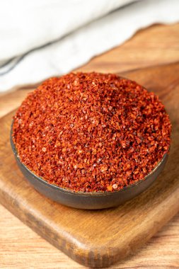 Red pepper flakes. Crushed chili pepper in bowl, dried chili flakes on wooden background. Close up