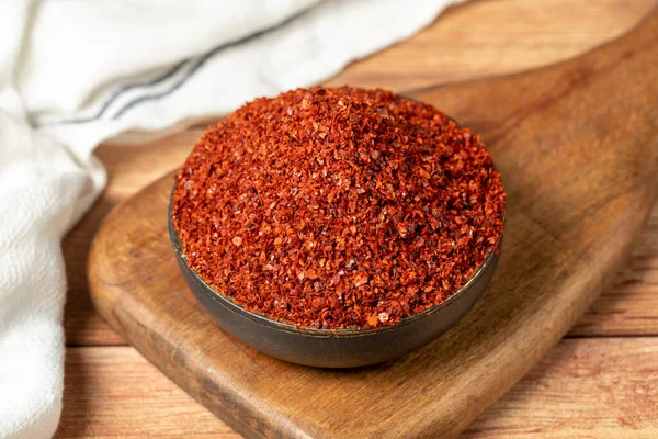Red pepper flakes. Crushed chili pepper in bowl, dried chili flakes on wooden background. Close up