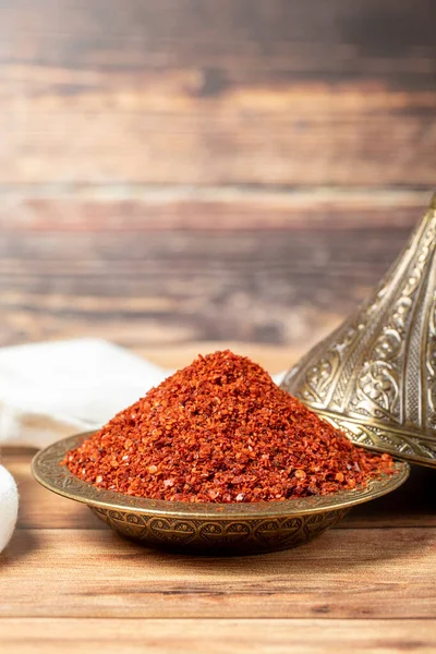 Red pepper flakes. Crushed chili pepper in bowl, dried chili flakes on wooden background. Close up