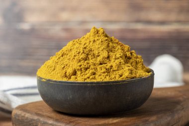 Curry Masala Powder. Turmeric powder or curry powder spice in a bowl on wooden background. indian spices. Dry spice concept. close up clipart