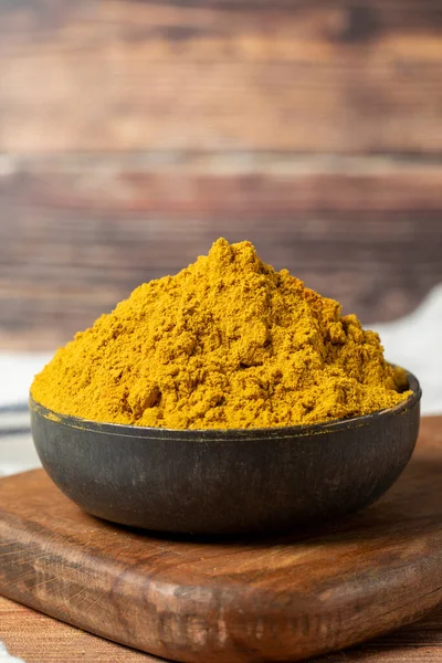 Curry Masala Powder. Turmeric powder or curry powder spice in a bowl on wooden background. indian spices. Dry spice concept. close up