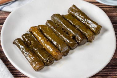 Delicious stuffing (yaprak sarma). Traditional food Turkish delicacies. Stuffed grape leaves rice in plate on wood floor. Close up