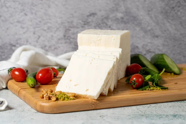 Ripe white cheese. Feta cheese made from cow\'s milk on a wooden serving board. Dairy products