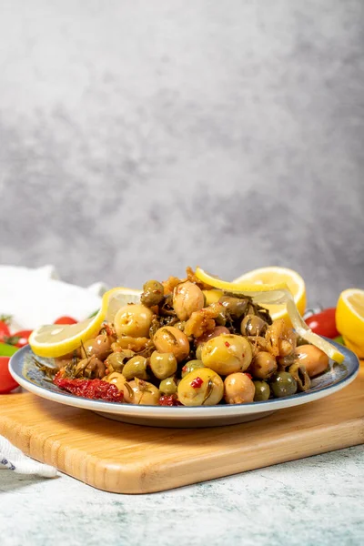 Special mixed olives prepared with green olives, dried red peppers, sun-dried tomatoes, thyme, walnuts and rosemary. Mixed olives with special sauce on a wooden serving plate