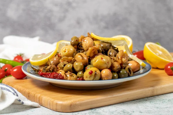 Special mixed olives prepared with green olives, dried red peppers, sun-dried tomatoes, thyme, walnuts and rosemary. Mixed olives with special sauce on a wooden serving plate. low angle view