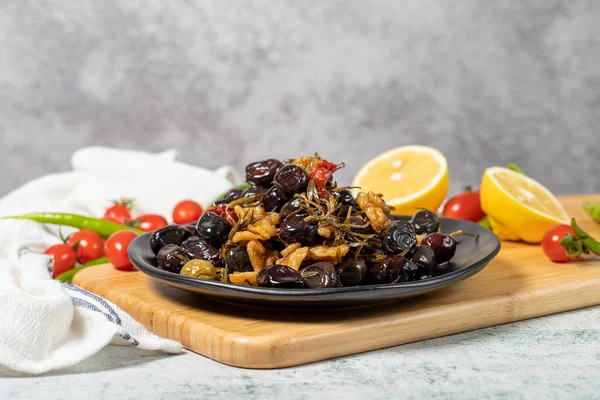 Mixed black olives. Special mixed olives prepared with dried red pepper, sun-dried tomatoes, thyme, walnuts and rosemary on a wooden serving plate. Low angle view