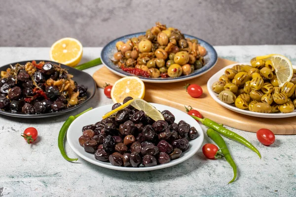 Olive varieties. Assortment of black and green olives on plate on gray background