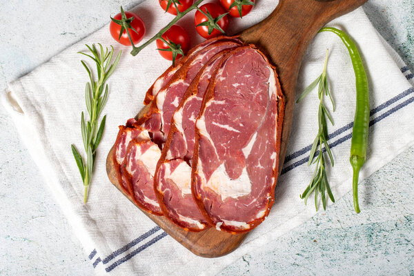 Beef ribeye pastrami. Slices of dried turkish bacon on a wooden serving board. Traditional Turkish delicacies. Local name pastirma. Top view