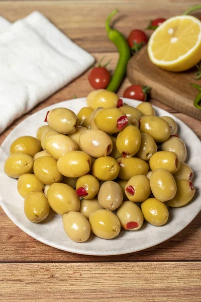 Stuffed olives. Green olives stuffed with dry peppers on a wooden background. Mediterranean flavors