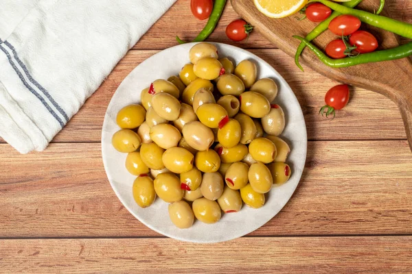 Stuffed olives. Green olives stuffed with dry peppers on a wooden background. Mediterranean flavors. Top view