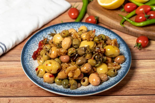 Mixed green olives. Green olive salad on wood background. Mediterranean flavors