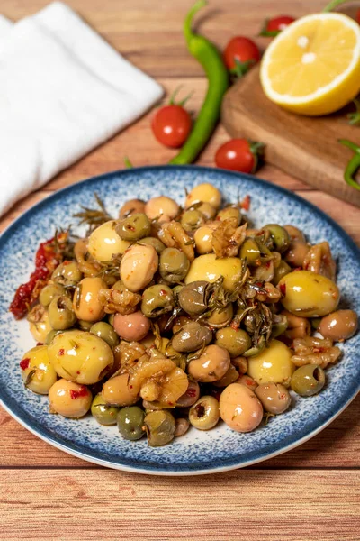 Mixed green olives. Green olive salad on wood background. Mediterranean flavors