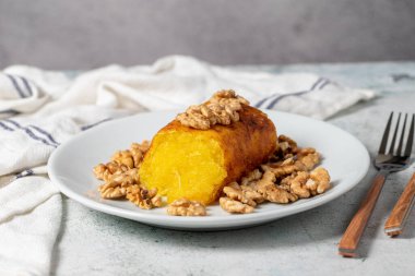 Gri arkaplanda şerbet olan incirli tatlı. Ceviz dolgulu incir tatlısı. Yerel adı Hatay incir tatlisi