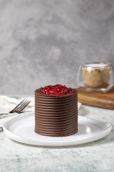 Chocolate and raspberry cake. Patisserie products. Chocolate covered cake on gray background.
