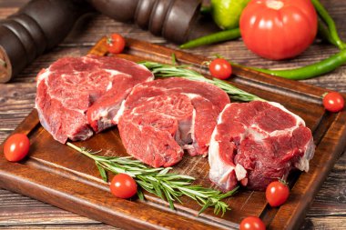 Çiğ kemiksiz biftek sapı. Ahşap servis tahtasının üzerinde pişmemiş et parçası.