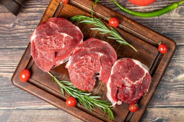 Çiğ kemiksiz biftek sapı. Ahşap servis tahtasının üzerinde pişmemiş et parçası. Üst görünüm