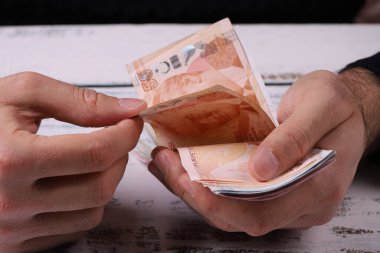 Genç adam elinde Türk banknotlarını sayıyor. Türk Lirası Dener veya TL