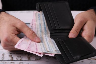 Genç adam elindeki cüzdanın içini gösteriyordu. Türk Lirası Dener veya TL