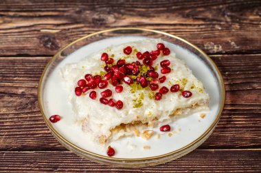 Gullac tatlısı. Ramazan tatlısı. Nar ve ahşap zemin üzerinde cam plaka ile süslenmiş Gullac. Sembolik gıda.