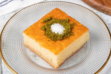 Revani tatlısı. Fıstıklı tatlı irmik keki. Ramazan tatlısı. Geleneksel Türk mutfağı lezzetleri. Gri arka planda şuruplu Revani tatlısı. Kapat.
