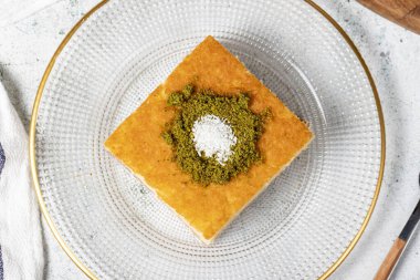 Revani tatlısı. Fıstıklı tatlı irmik keki. Ramazan tatlısı. Geleneksel Türk mutfağı lezzetleri. Gri arka planda şuruplu Revani tatlısı. Üst görünüm