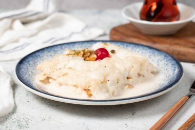 Cevizli Gullac tatlısı. Ramazan tatlısı. Geleneksel Türk mutfağı lezzetleri. Kirazlı Gullac tatlısı, şam fıstığı ve gri arka planda ceviz.