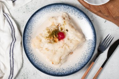 Cevizli Gullac tatlısı. Ramazan tatlısı. Geleneksel Türk mutfağı lezzetleri. Kirazlı Gullac tatlısı, şam fıstığı ve gri arka planda ceviz. Üst görünüm