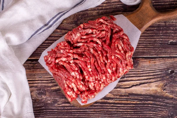 Minced meat on wood background. Raw minced cow meat or ground meat. Top view