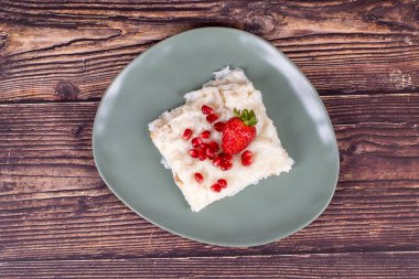 Nar ve çilekli Gullac tatlısı. Ramazan tatlısı. Ahşap arka planda cevizli Gullac tatlısı. Üst görünüm