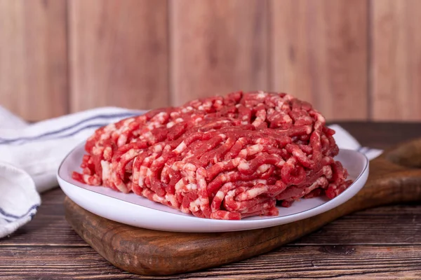 牛は皿の上でひき肉 木の背景に新鮮な挽肉 — ストック写真