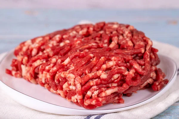 Beef minced on the plate. Fresh ground beef on wood background. Close up